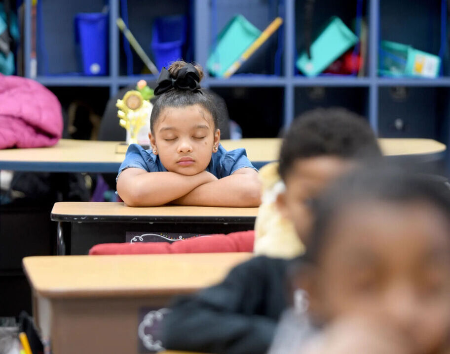 Student resting their head on their arms with their eyes closed, listening to Mindful Music.