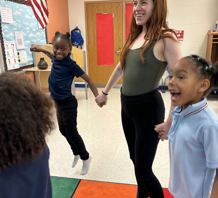 Students jump while holding hands and singing.