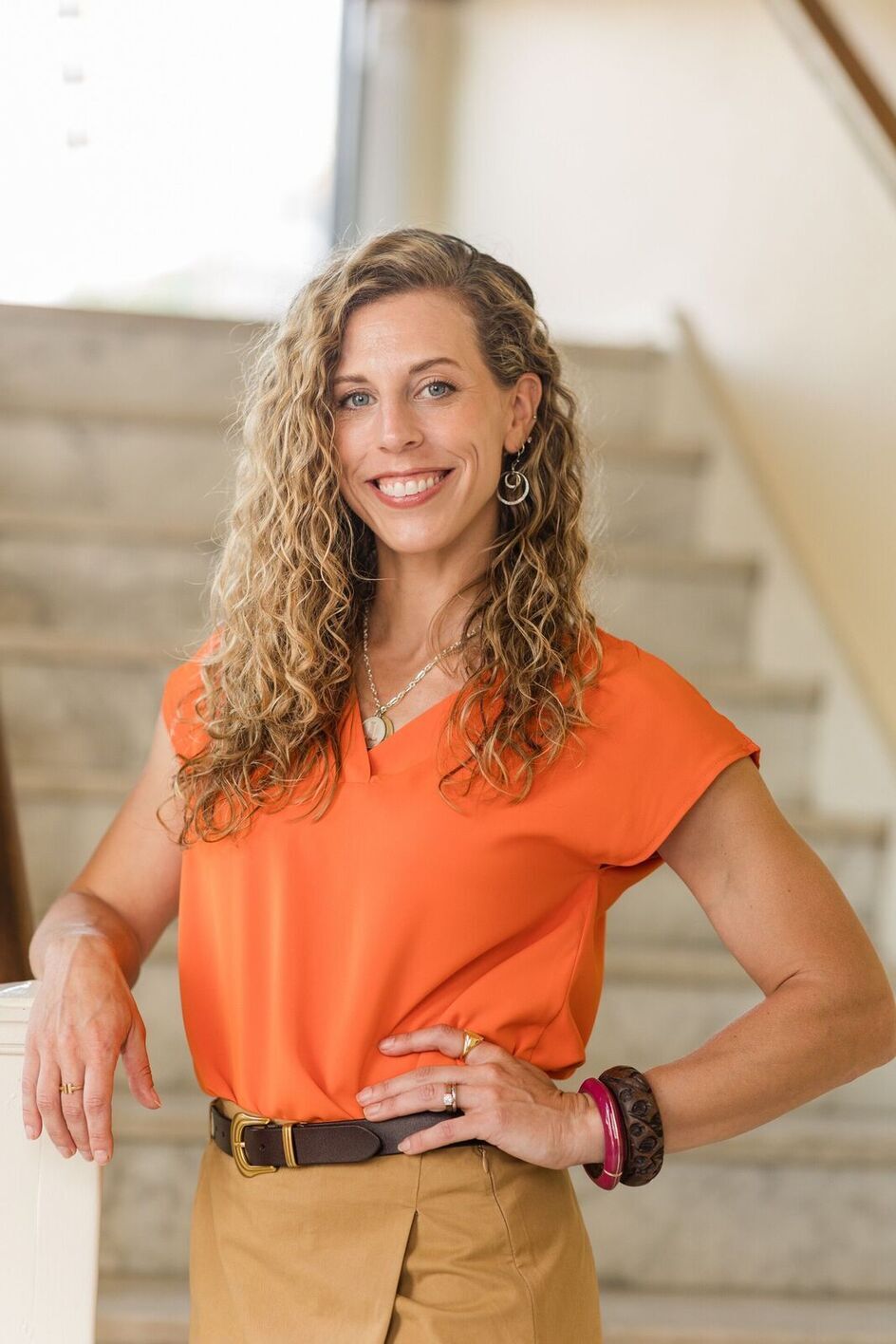 woman in orange shirt smiling at camera