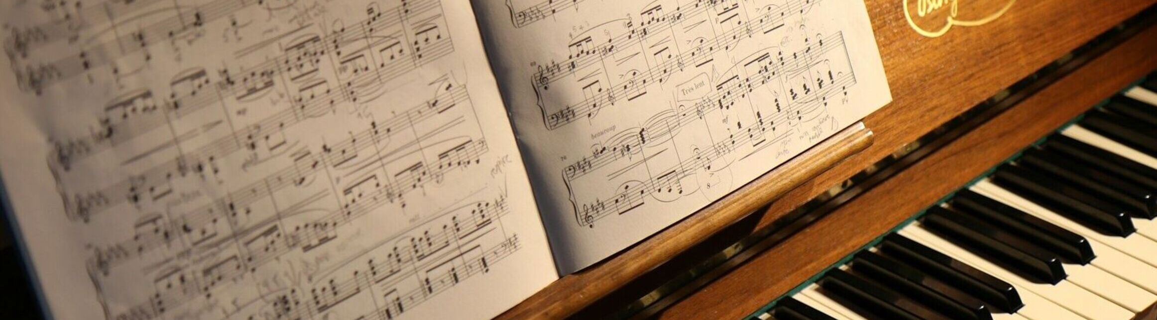 Two pages of sheet music on a wooden piano with black and white keys.