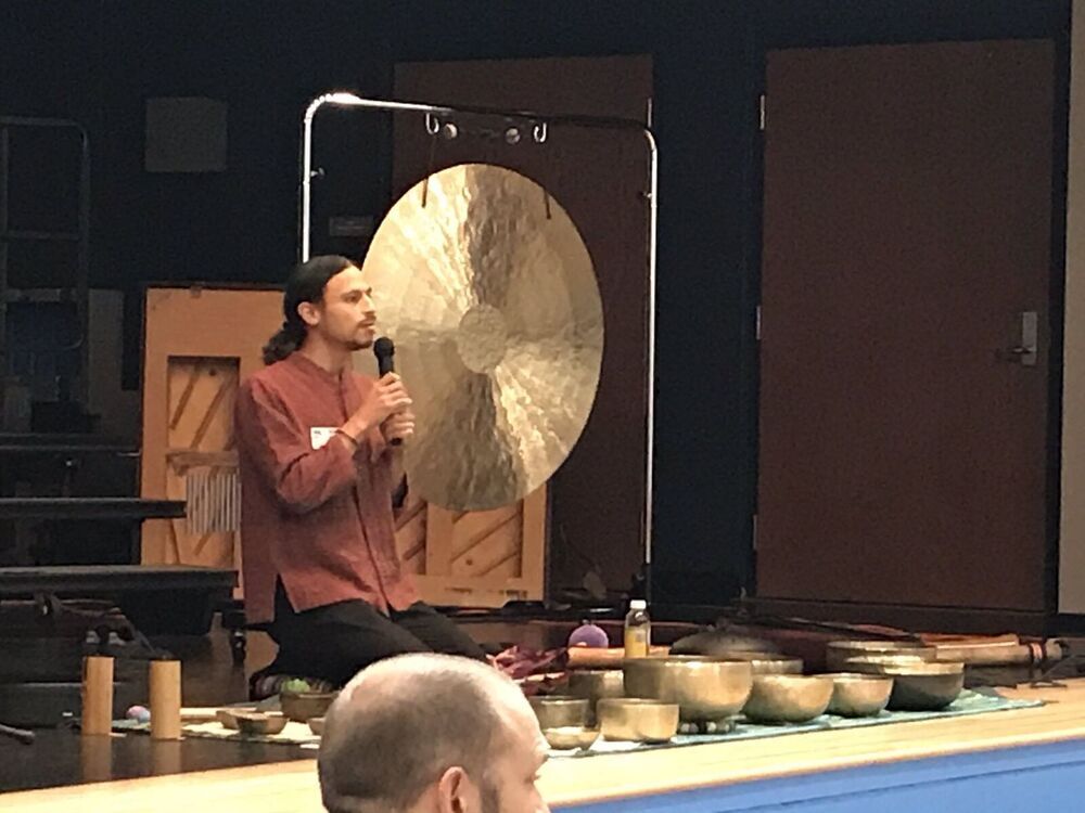 Max Raphael stands on a stage showing chimes and gongs.
