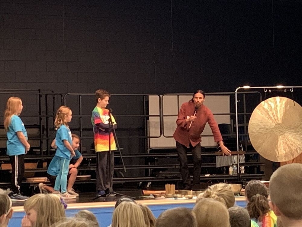Max Raphael stands with four students on a stage showing chimes and gongs.