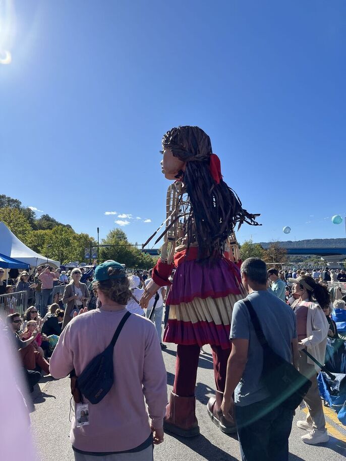 Little Amal walks through a crowd.