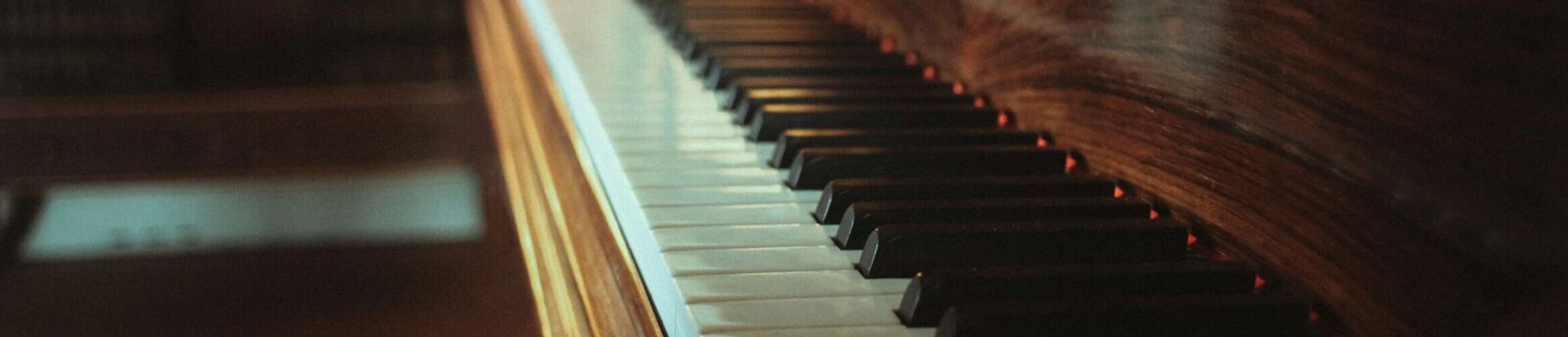 A side closeup photo of all 88 keys on a wooden grand piano.